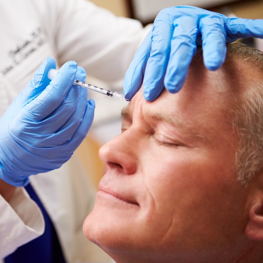 man receiving injectable needle treatment to brow